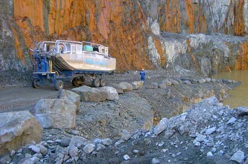 A man is standing by a boat by a lake.